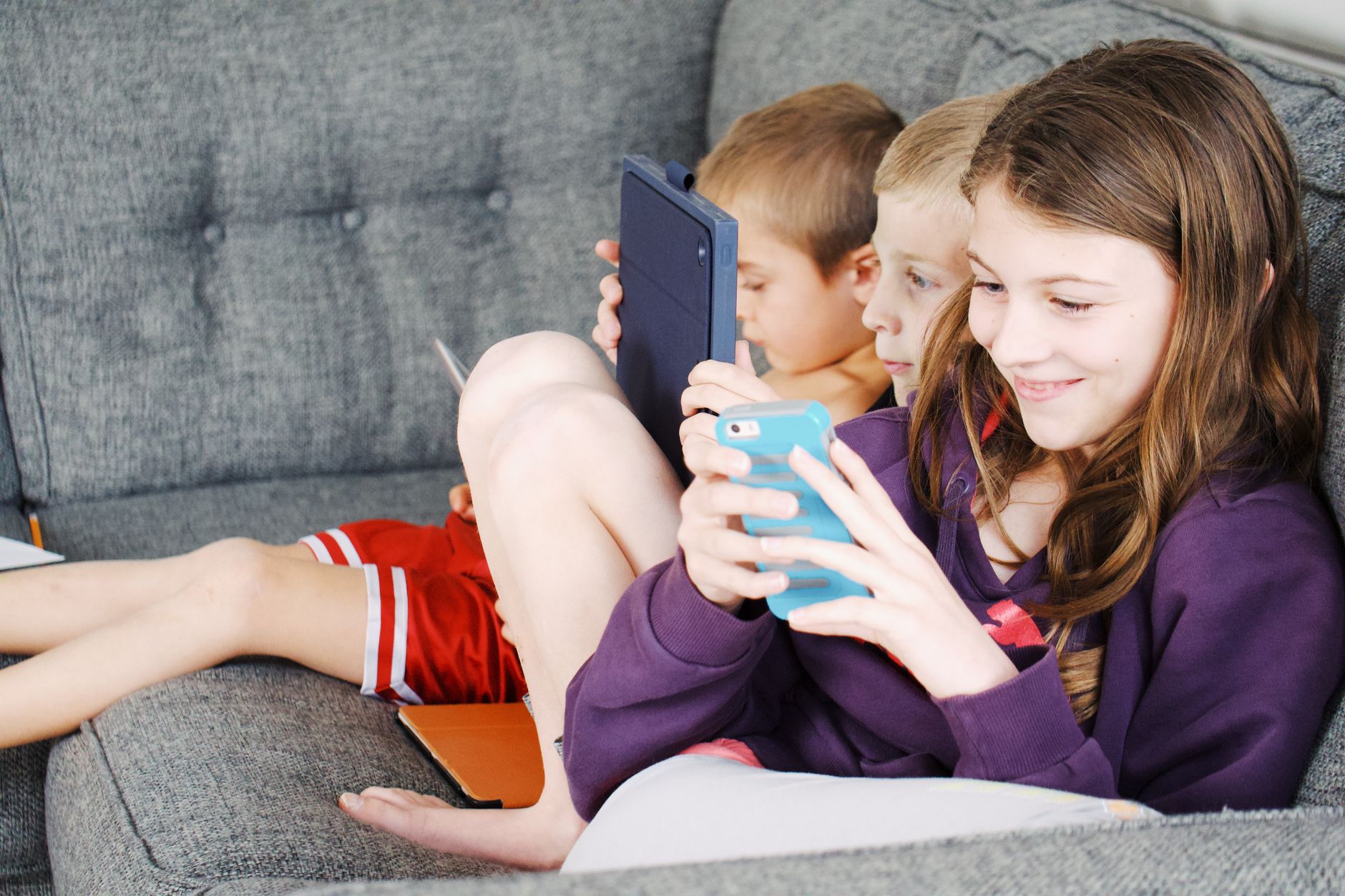 photo of kids sitting on gray sofa